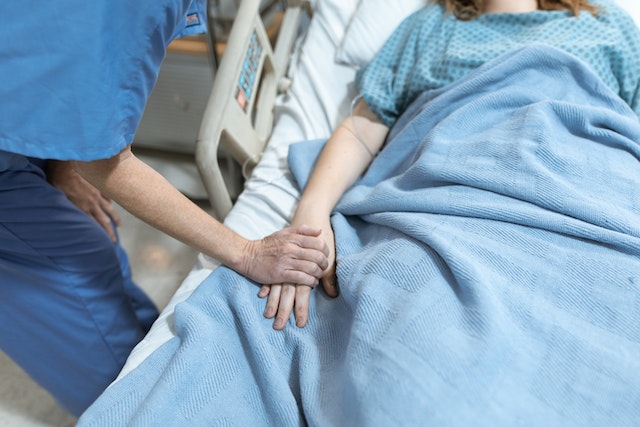 someone in hospital bed having hand held