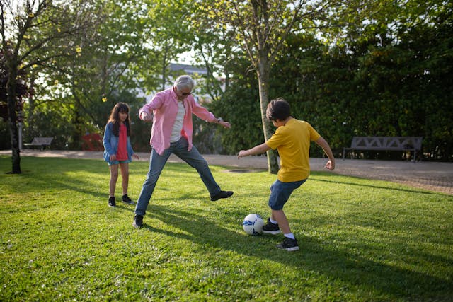 grandfather playing soccer with two grandchildren