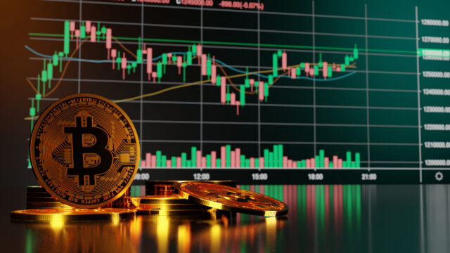 Several gold Bitcoin tokens are stacked on a reflective surface in the foreground, with a digital cryptocurrency price chart and candlestick graph displayed on a screen in the background—an essential image for any cryptocurrency estate plan.